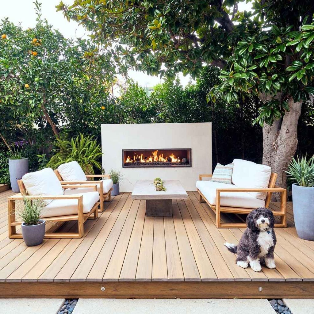 Wooden outdoor furniture by pool surrounded by greenery