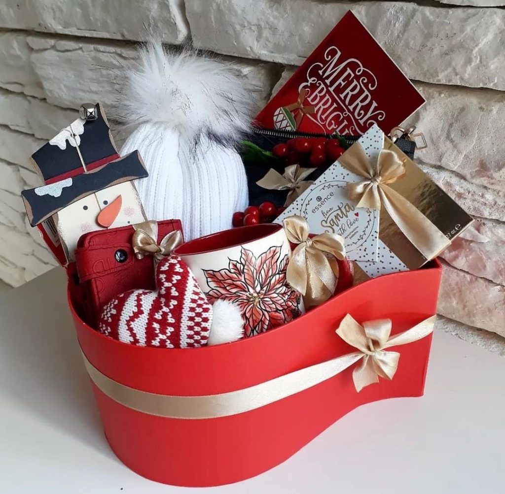 Festive red Christmas basket with cozy winter accessories and treats.