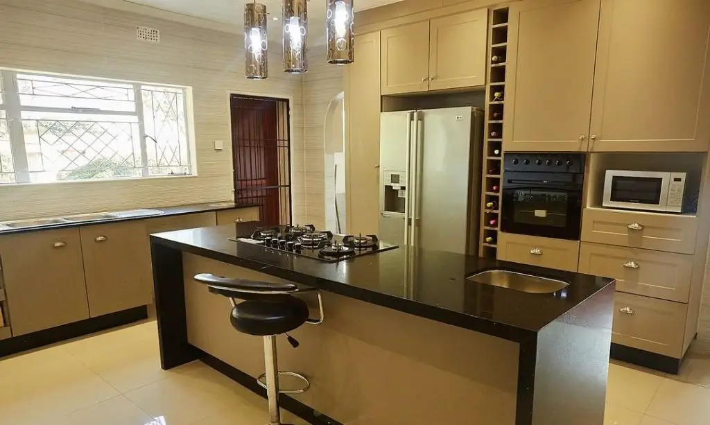Spacious kitchen with cream cabinets and black island countertop