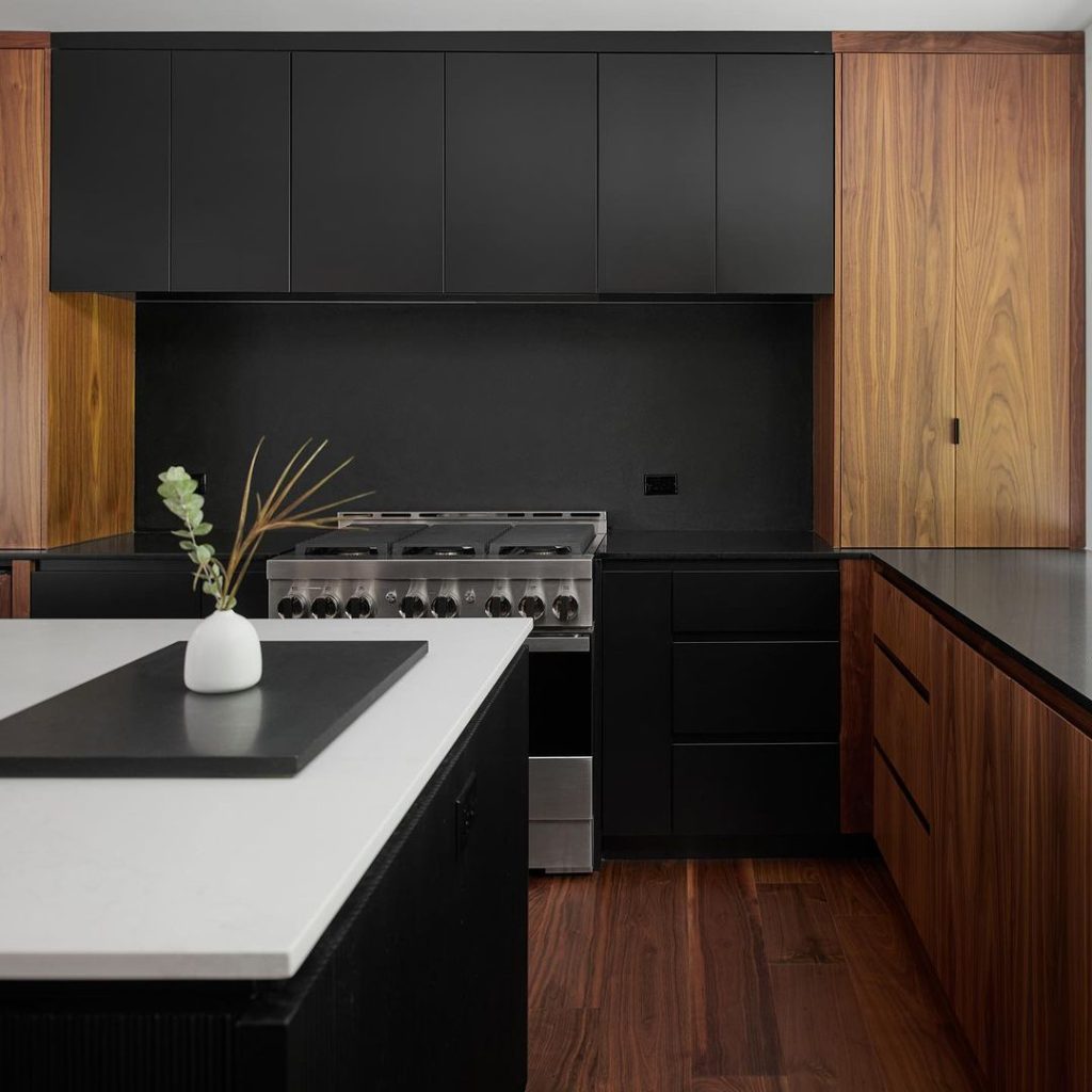 Modern black kitchen with walnut accents and white island