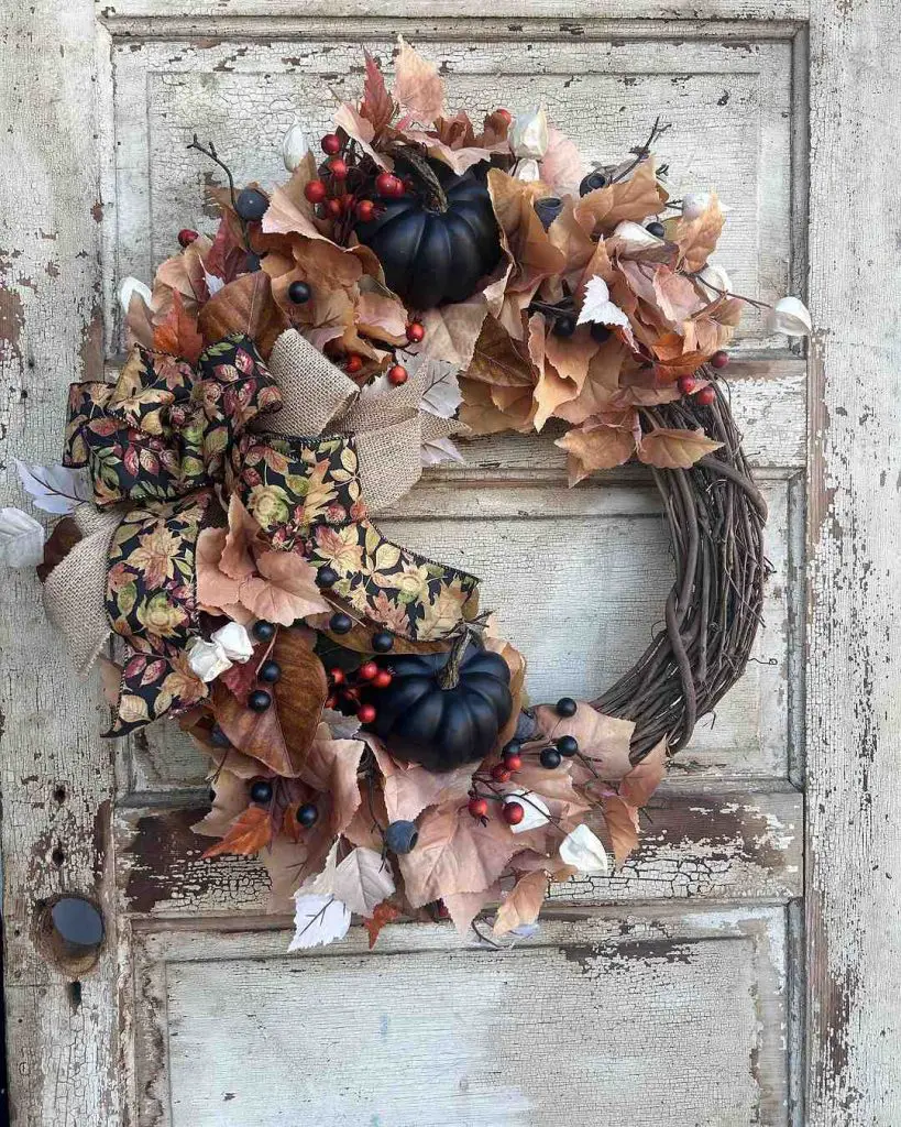 Rustic wreath with black pumpkins and autumn leaves