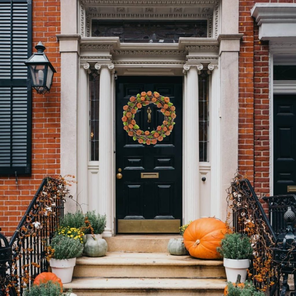 Elegant townhouse entrance decorated for fall with pumpkins and wreath