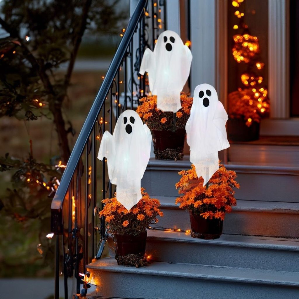 Glowing ghost decorations on porch steps with flowers