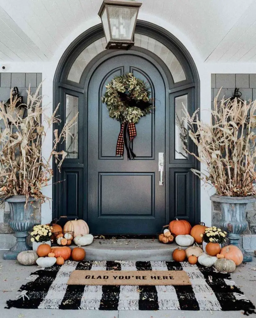 Elegant fall porch with dark door pumpkins and wreath