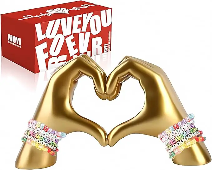 A golden sculpture of two hands forming a heart shape is adorned with colorful beaded bracelets.