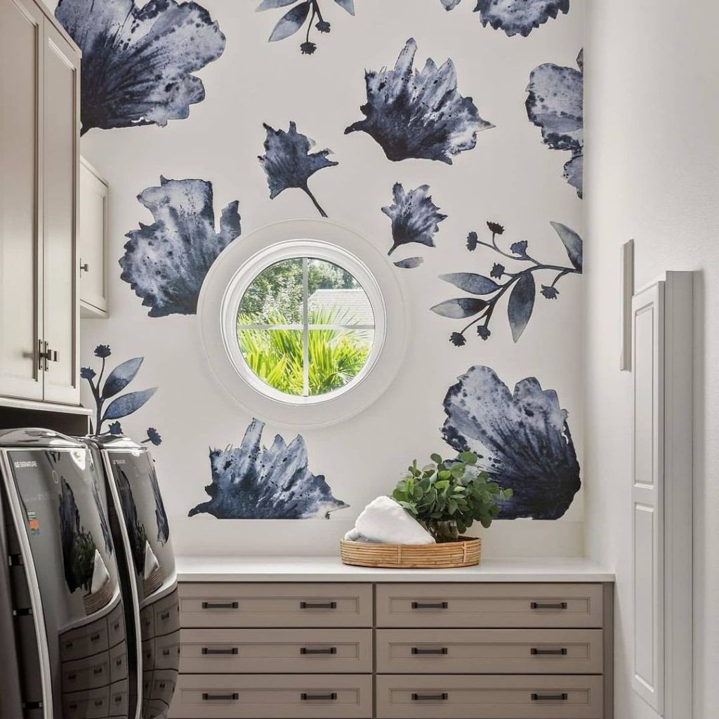 Laundry room with navy floral wallpaper and round window.