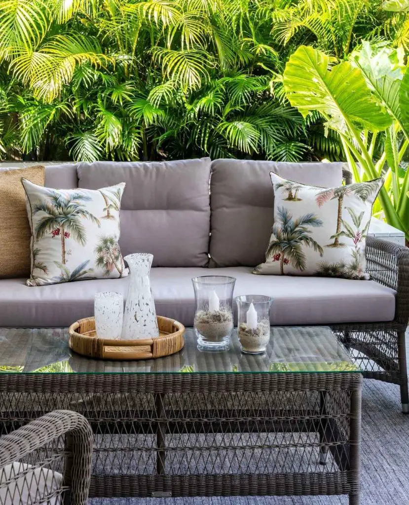 Outdoor sofa with tropical pillows against lush palm background