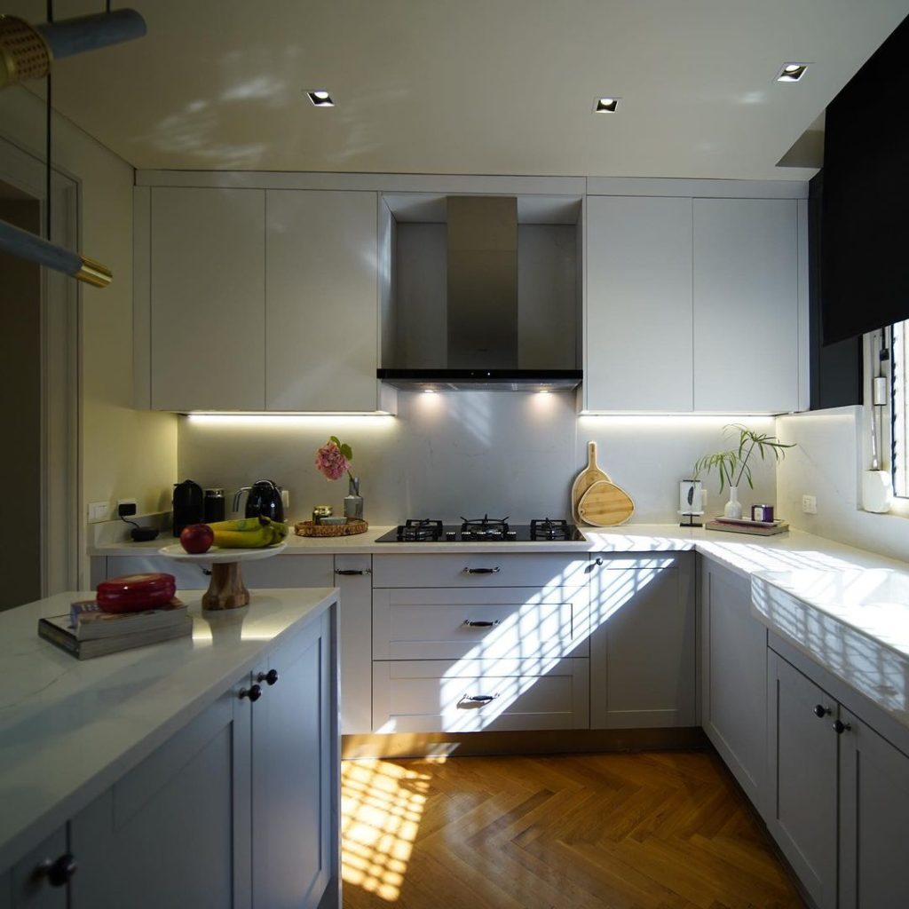 Bright U-shaped kitchen with white cabinets, herringbone floor