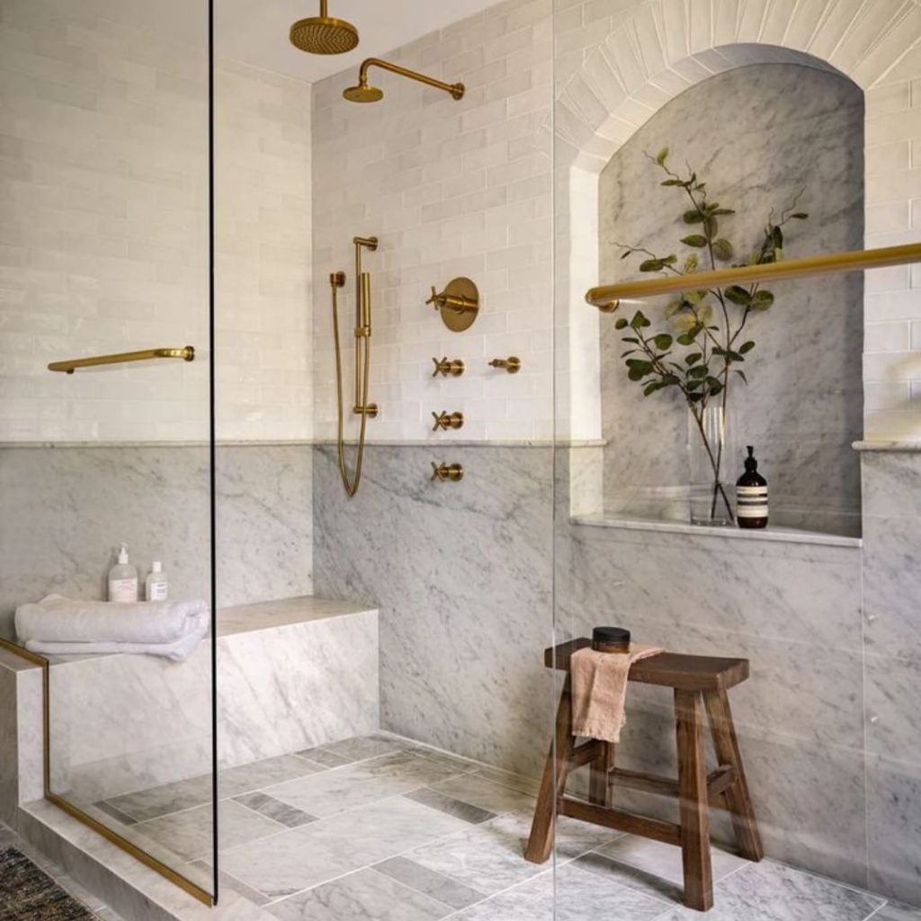 Marble bathroom with gold fixtures and arched niche.