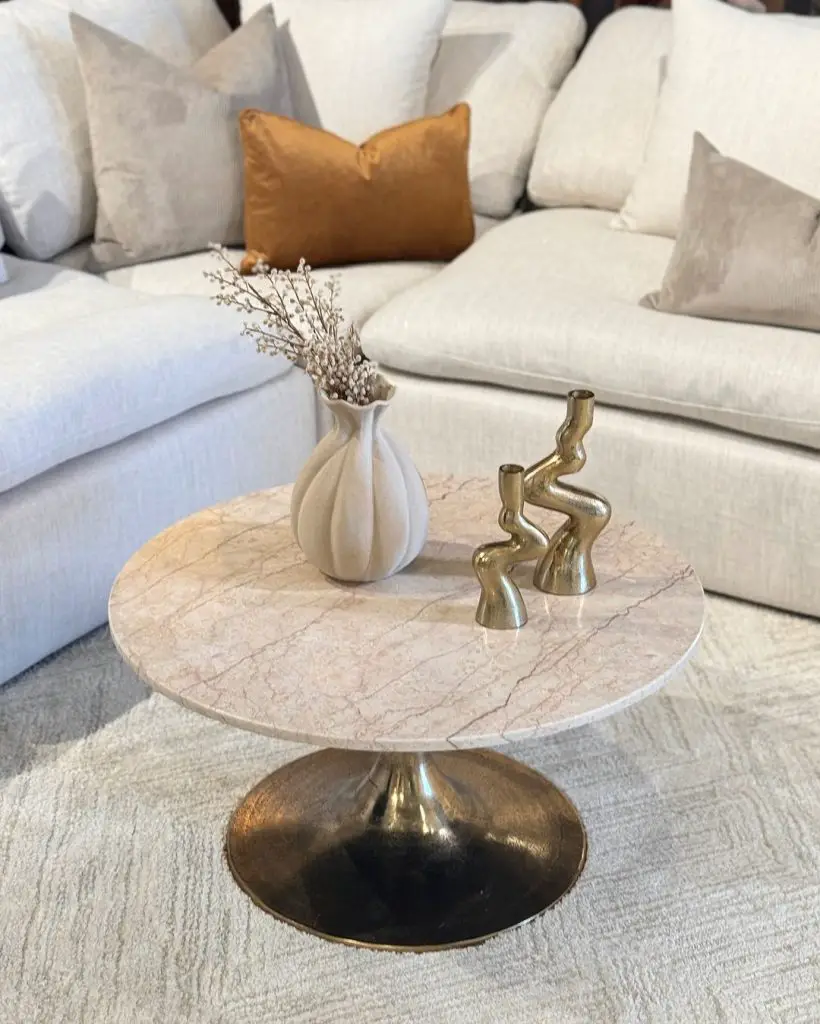 Marble coffee table with gold base, decorative items, and white sofa
