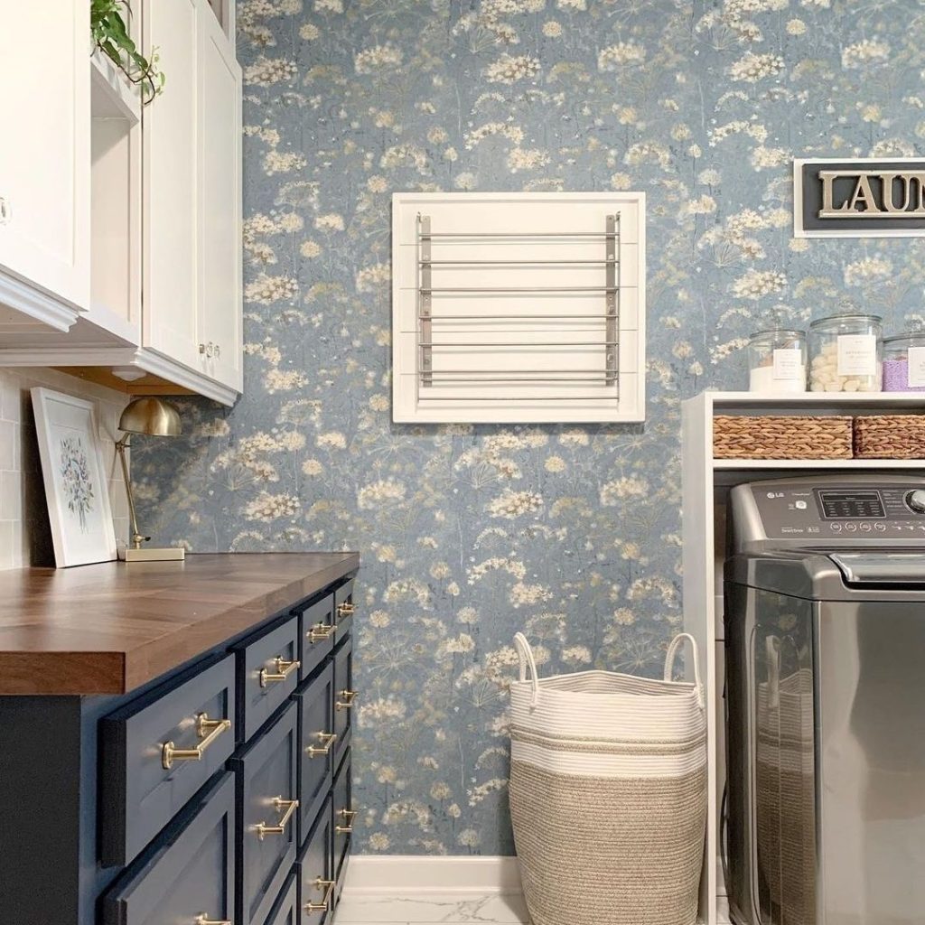 Laundry room with floral wallpaper and navy cabinets.