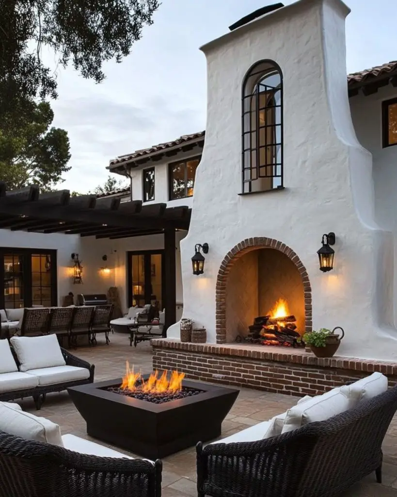 Luxurious patio with fireplace and fire pit table against Spanish-style house