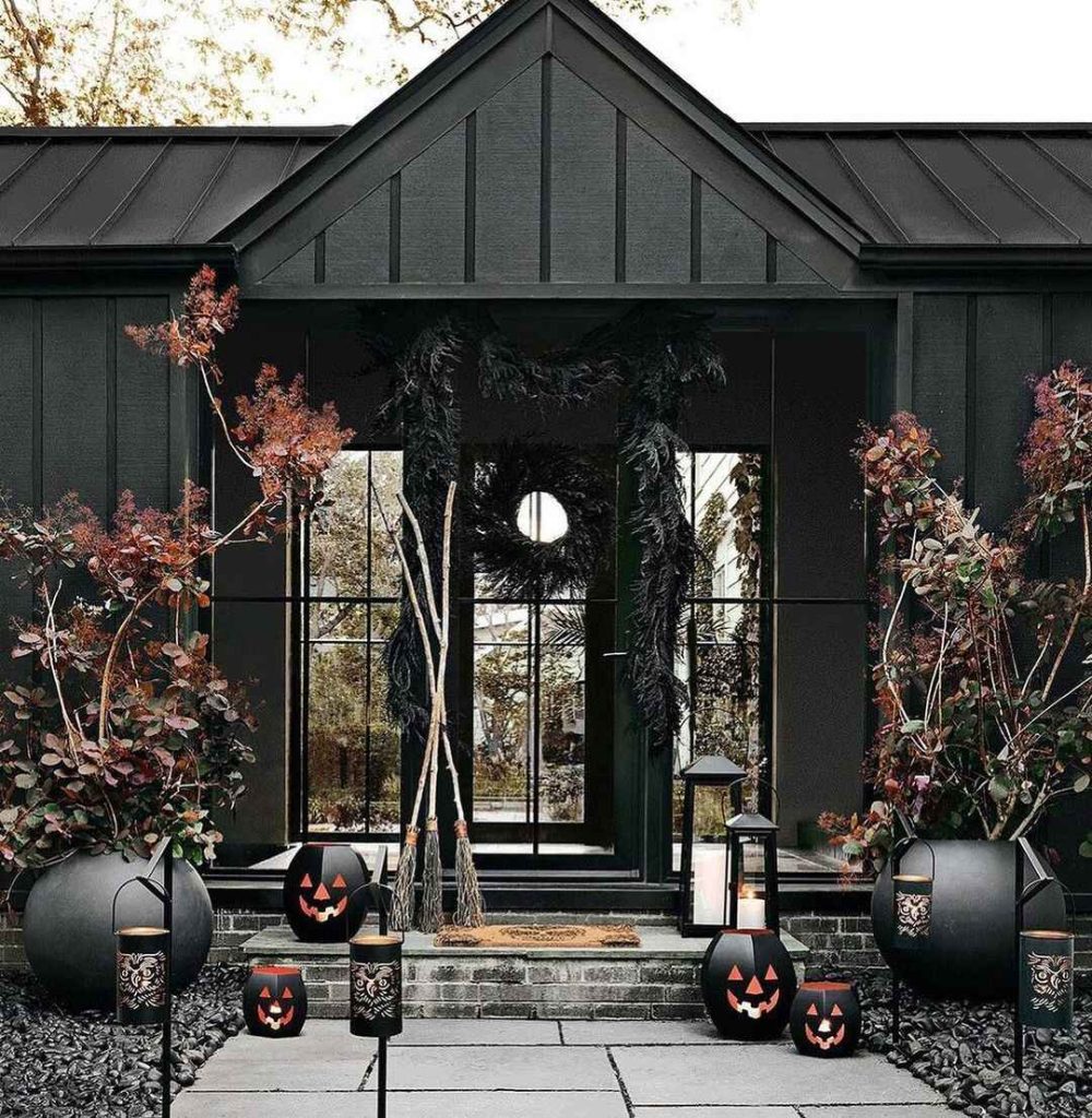 Black porch decorated with glowing pumpkins and autumn foliage