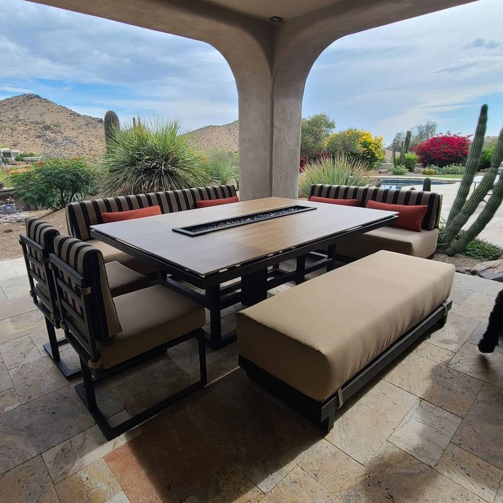 Modern patio dining set with fire table overlooking desert landscape.