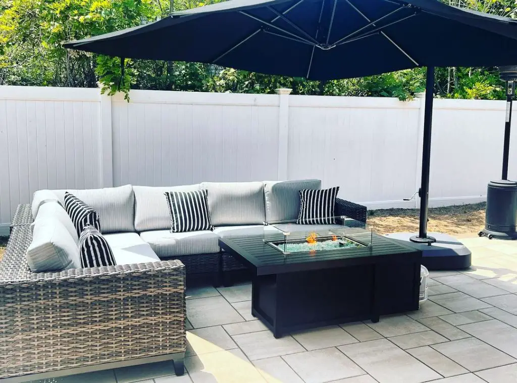 Patio with gray wicker sofa fire table and navy umbrella