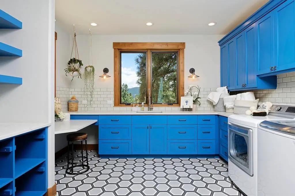 Modern blue laundry room with geometric flooring, ample storage, and natural light.