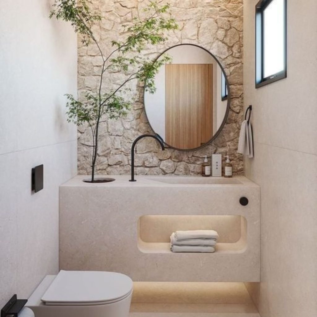 Small bathroom with stone wall circular mirror and plant