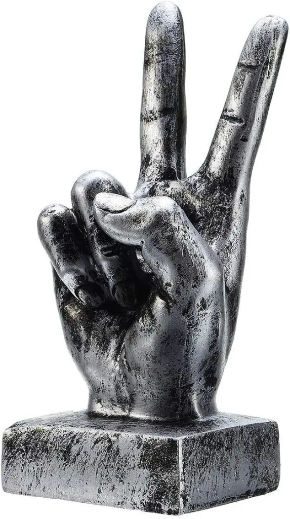 A metallic sculpture of a hand showing the peace sign with the index and middle fingers raised and other fingers folded.