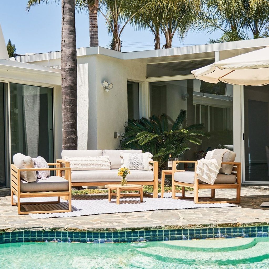 Modern poolside patio with teak furniture and palm trees