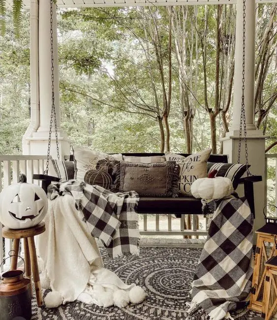 Cozy porch swing with buffalo check blankets and pumpkins