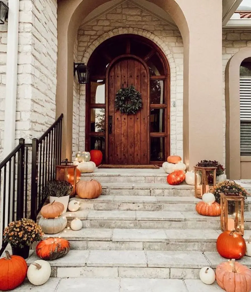 Stone steps decorated with pumpkins and lanterns leading to wooden door