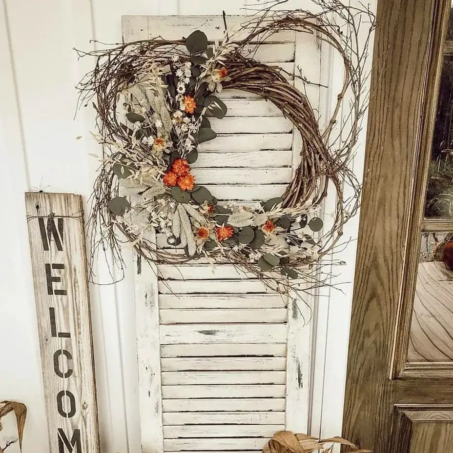 Twig wreath with dried flowers on vintage shutter with welcome sign