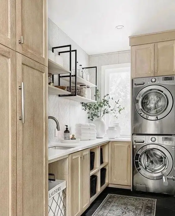Modern farmhouse laundry room with light wood cabinets and stacked appliances