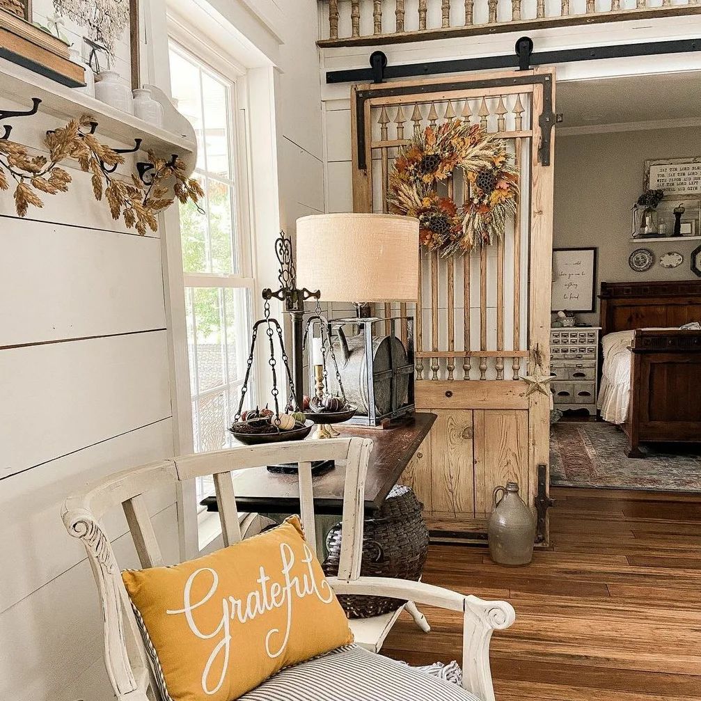 Farmhouse interior with autumn wreath on barn door and cozy chair
