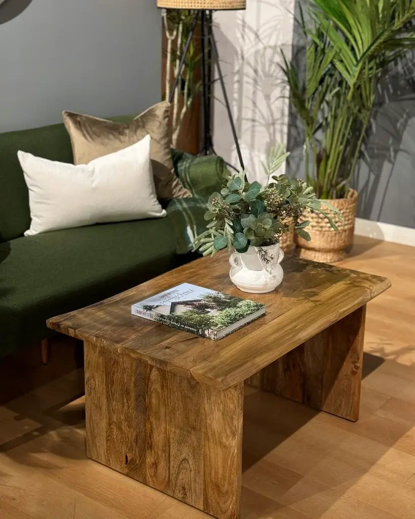 Rustic wooden coffee table with plants, book, and green sofa