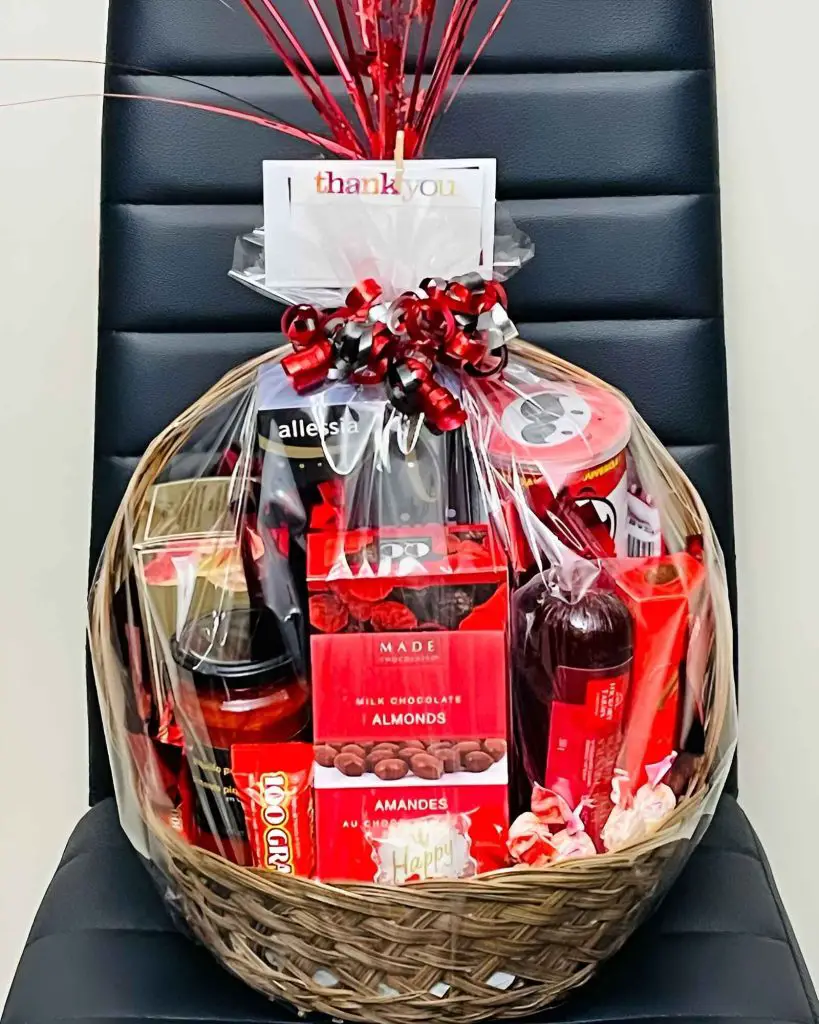 Gift basket with wine chocolates and snacks wrapped in red ribbons