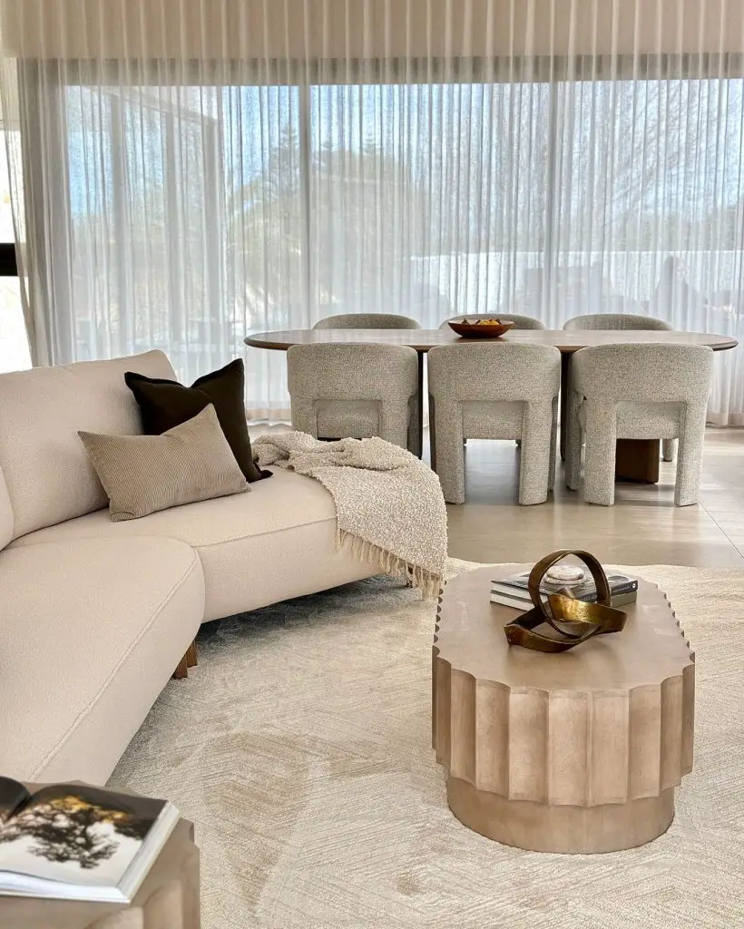 Modern living room with cream sofa, sculptural dining chairs, and textured coffee table