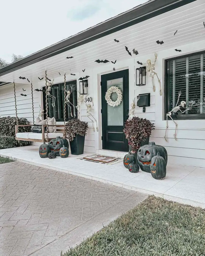 Halloween porch with climbing skeletons bats and dark pumpkins