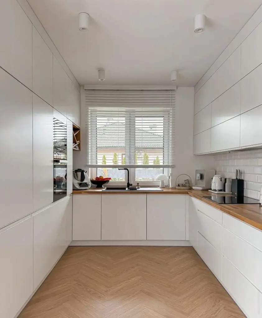Bright white galley kitchen with wood countertops and herringbone floor