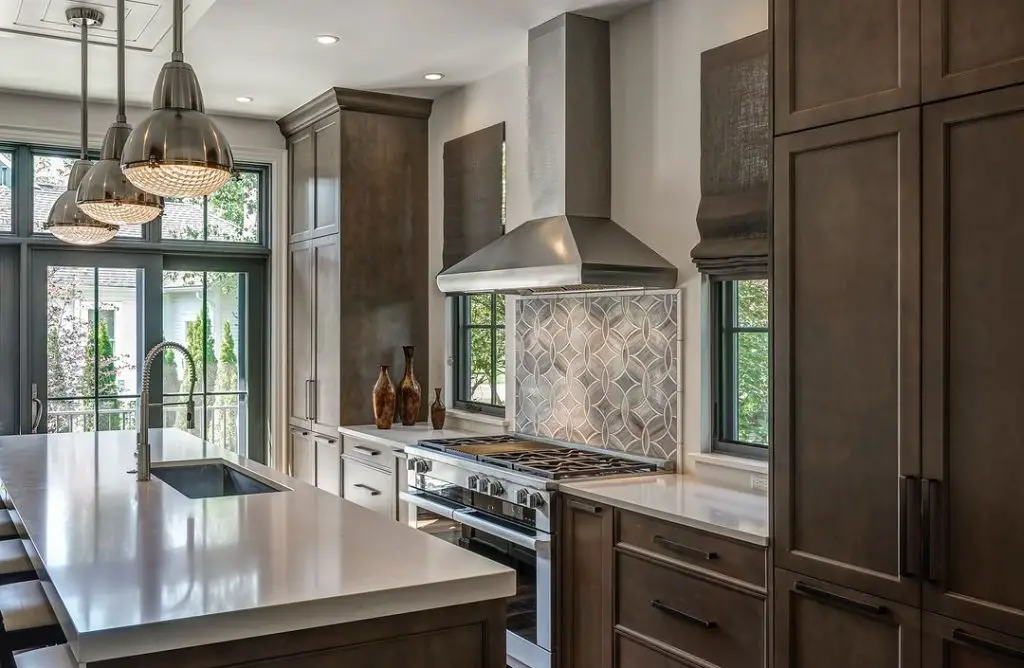 Modern kitchen with dark cabinets geometric backsplash and steel appliances
