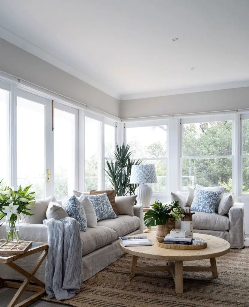 Bright sunroom with round wooden coffee table and comfortable sofas
