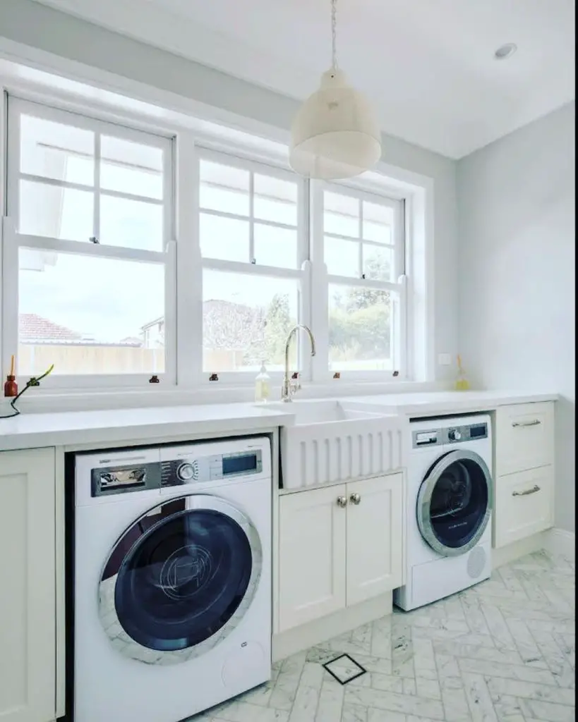 Bright laundry room with large windows white appliances and marble floor