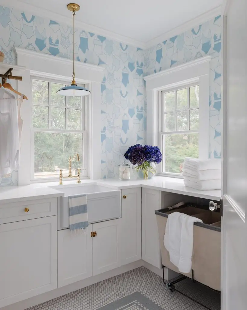 Bright laundry room with swimsuit wallpaper and white cabinets.
