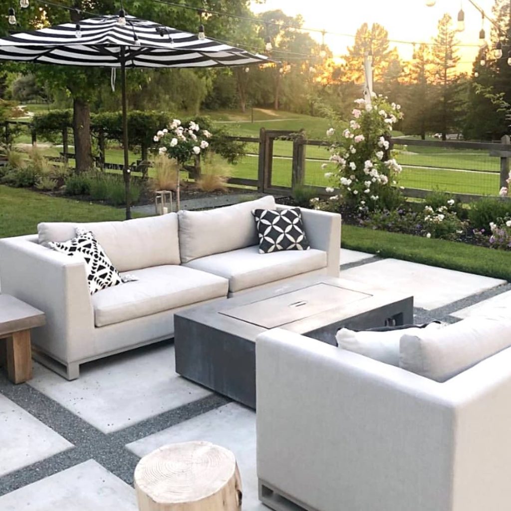 Modern patio furniture with striped umbrella overlooking garden