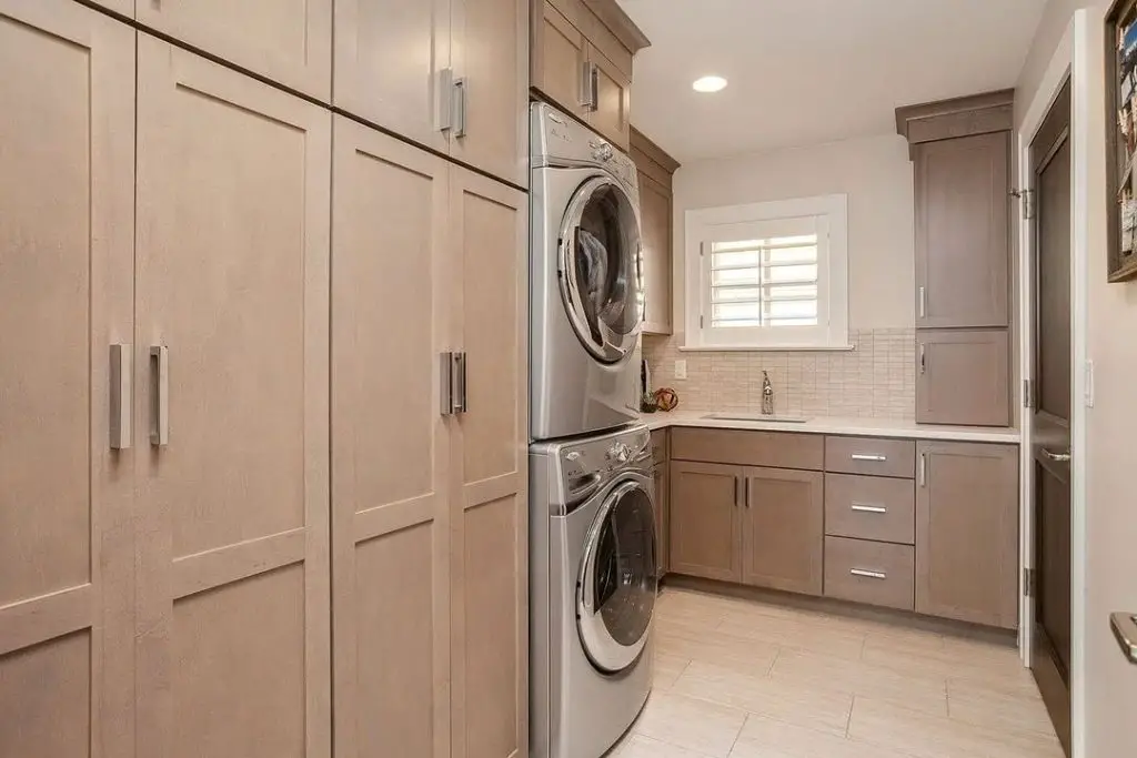 Taupe laundry room with stacked appliances and ample storage