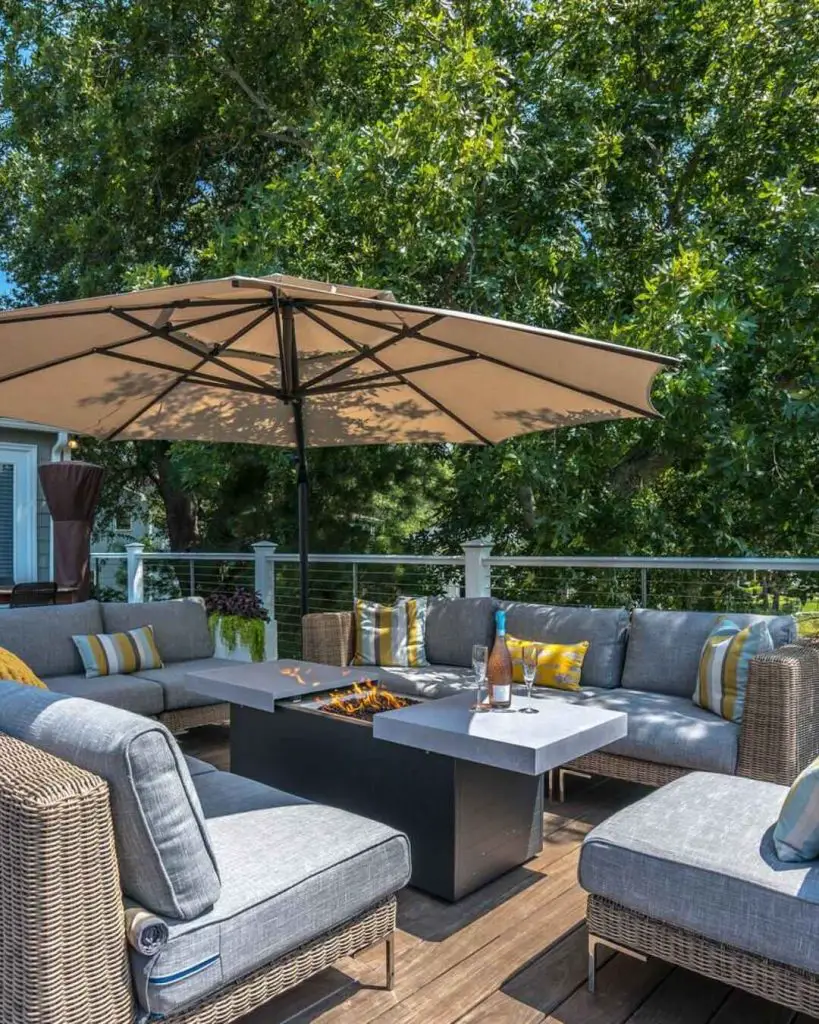 Cozy rooftop deck with fire pit table and wicker furniture under large umbrella