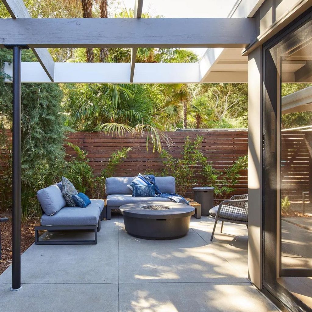 Modern patio with blue sofas fire pit and tropical plants