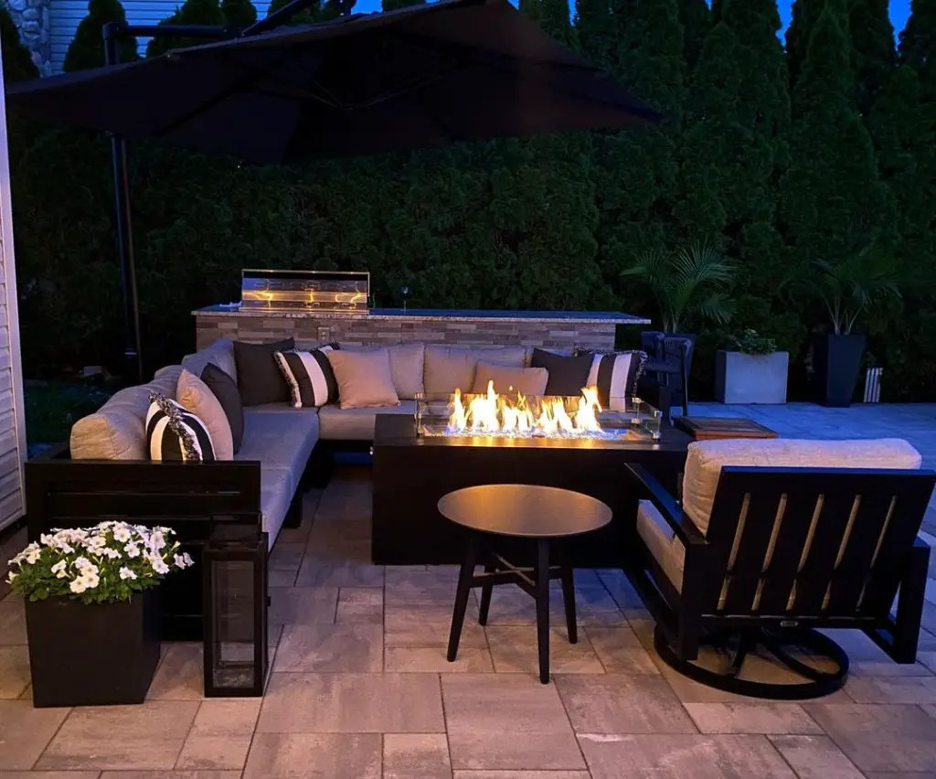 Nighttime patio with lit fire table and sectional sofa