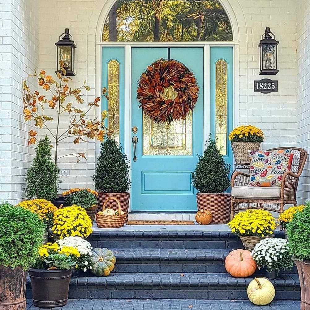 Colorful fall porch with blue door wreath mums and pumpkins