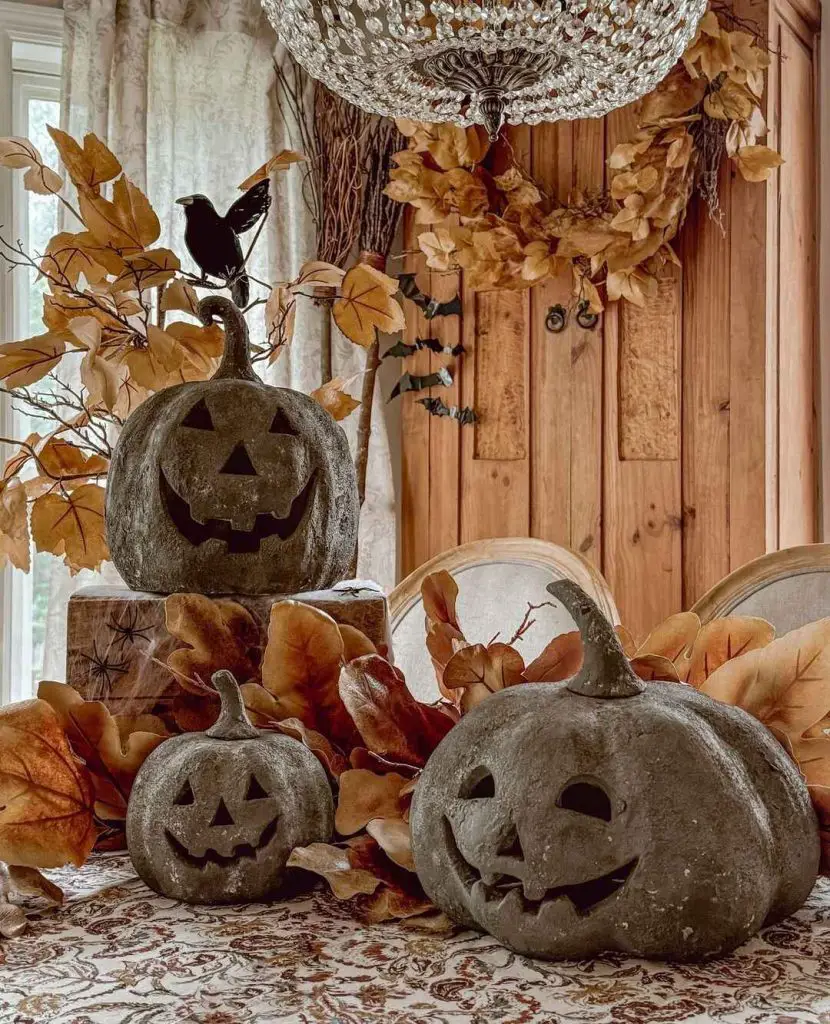 Stone jack-o'-lanterns with fall leaves under crystal chandelier.