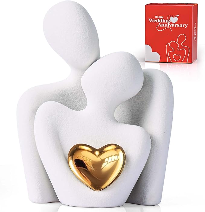 A white abstract sculpture of two intertwined figures holding a gold heart.