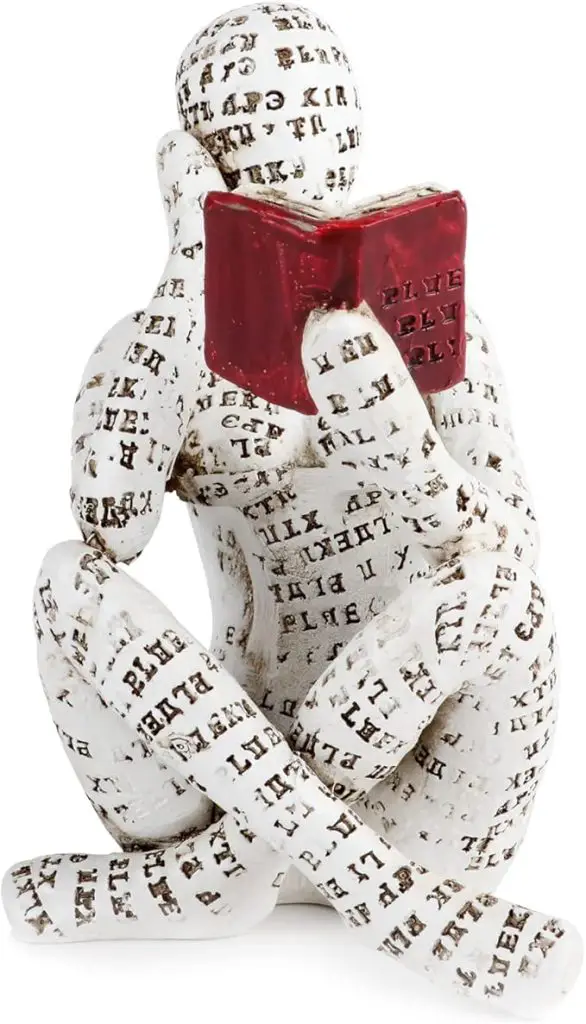 A white sculpture of a humanoid figure covered in black text sits cross-legged, holding and reading a small red book.