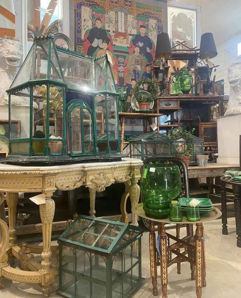 Vintage green tabletop greenhouse on ornate table in antique shop