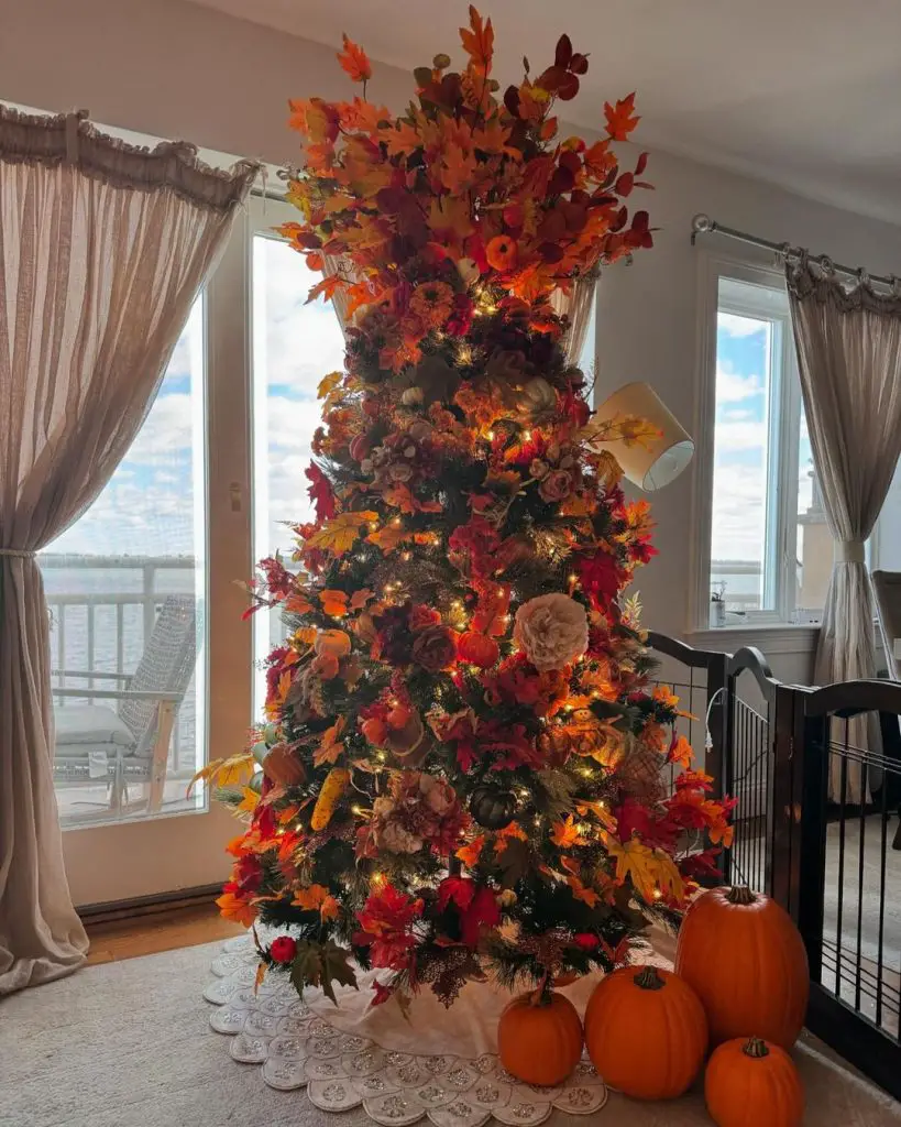 Autumn decorated Christmas tree with maple leaves and pumpkins against waterfront windows