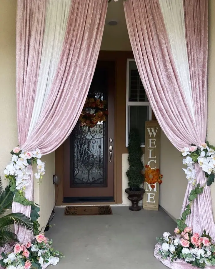 Pink curtained entrance with floral arrangements and welcome sign
