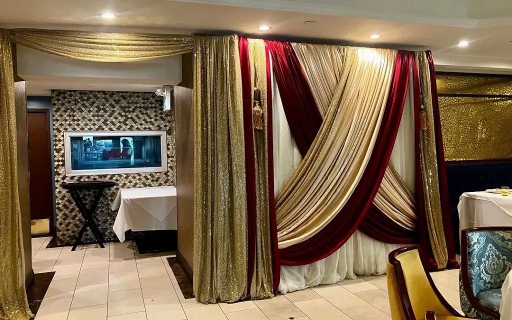 A wedding reception under hanging crystal drapes on a draped banquet table.